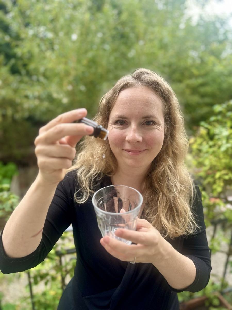 Pauline verse une goutte d'huile essentielle dans un verre d'eau