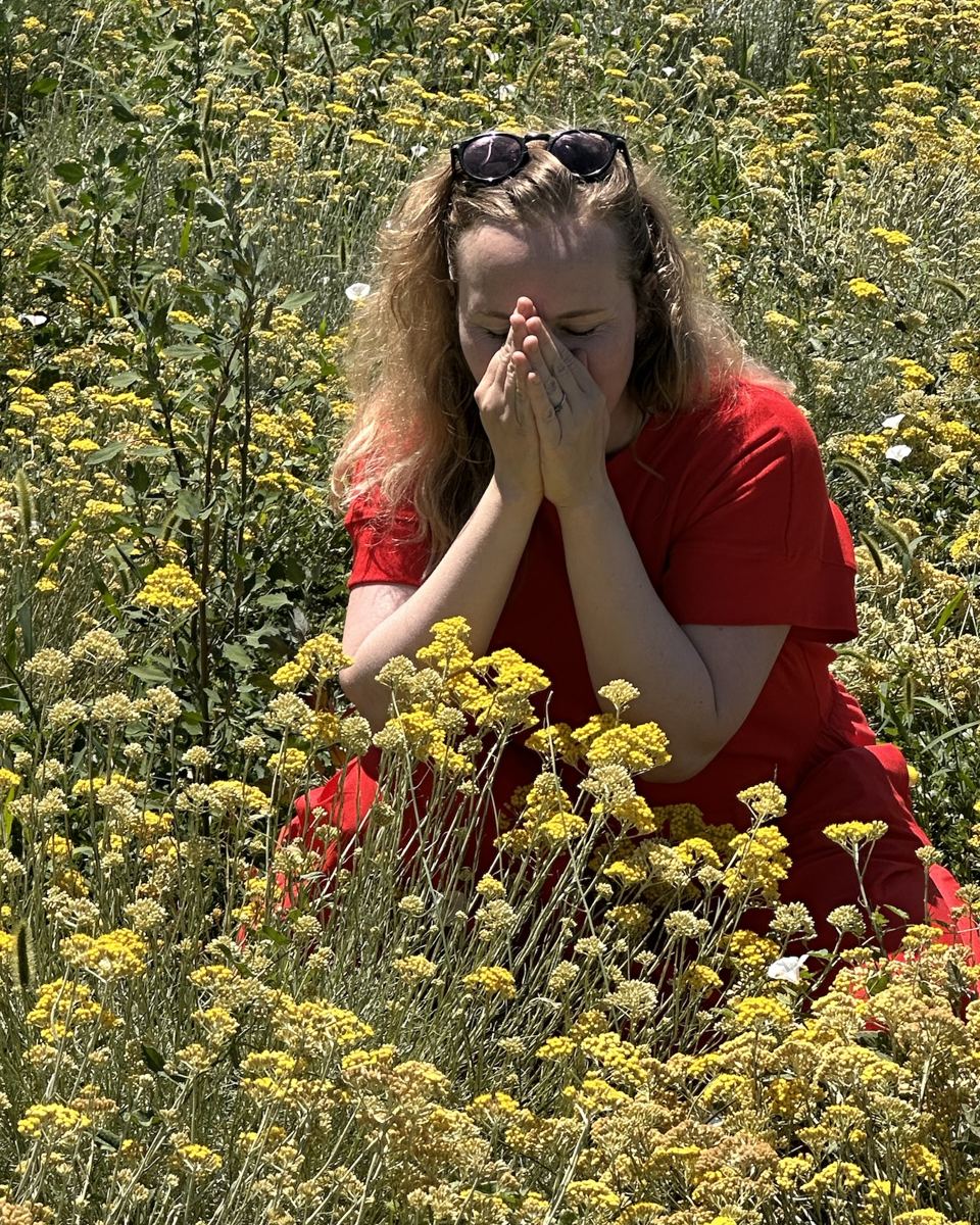 Pauline atmet, die Hände gefaltet, zwischen Blumen